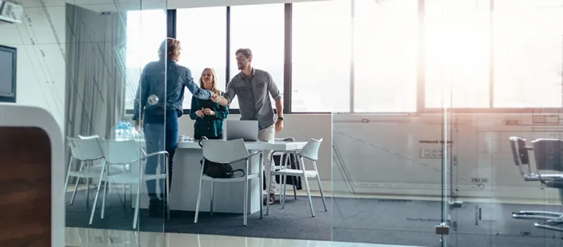 Business people shaking hands after meeting in board room. Businessman shaking hands with female in conference room at office.